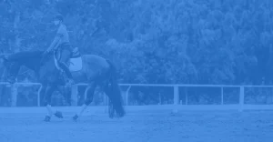 A person wearing a helmet rides a horse in an outdoor arena, framed by trees and a white fence. The image has a blue overlay, hinting at the spirit of Round 2023 or a 30 Days Challenge in equestrian training.