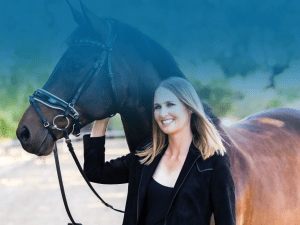 A smiling woman with straight blonde hair stands outdoors next to a dark brown horse, holding its bridle. The background features blurred greenery and subtle blue gradient patterns in the upper part of the image.