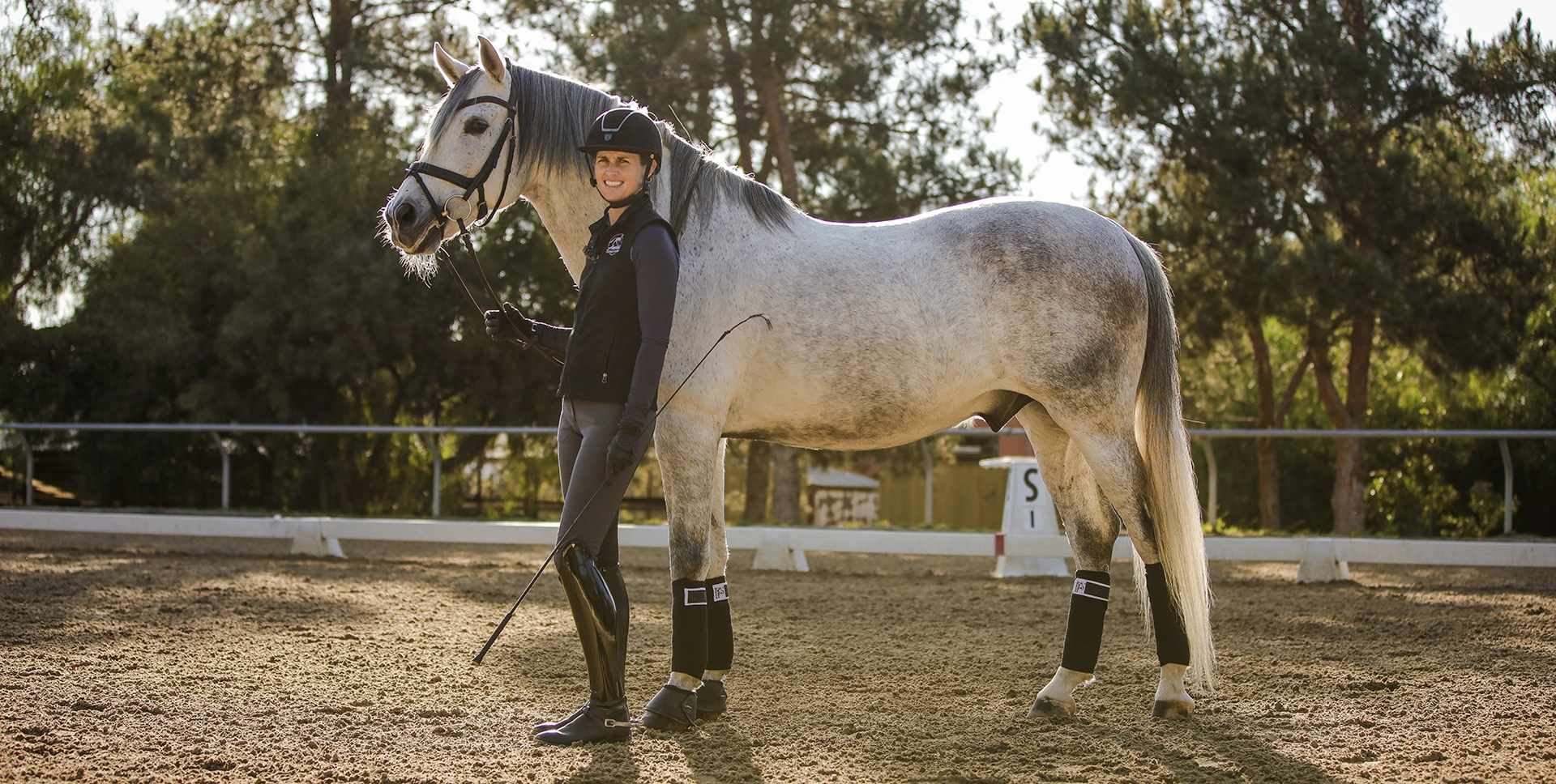 Amelia Newcomb posing and smiling with her horse Mercurio.