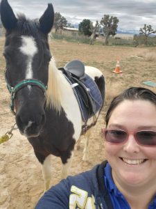 Breanna Erikson Gunter posing and smiling with her horse.