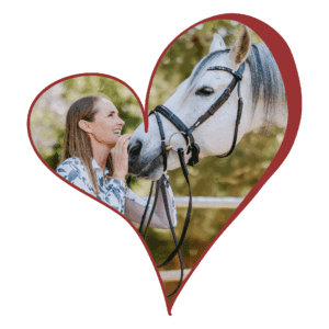 A woman smiles and touches the muzzle of a white horse. Both are framed together inside a large, red heart outline against a light background, capturing the bond that dressage foundations help create.